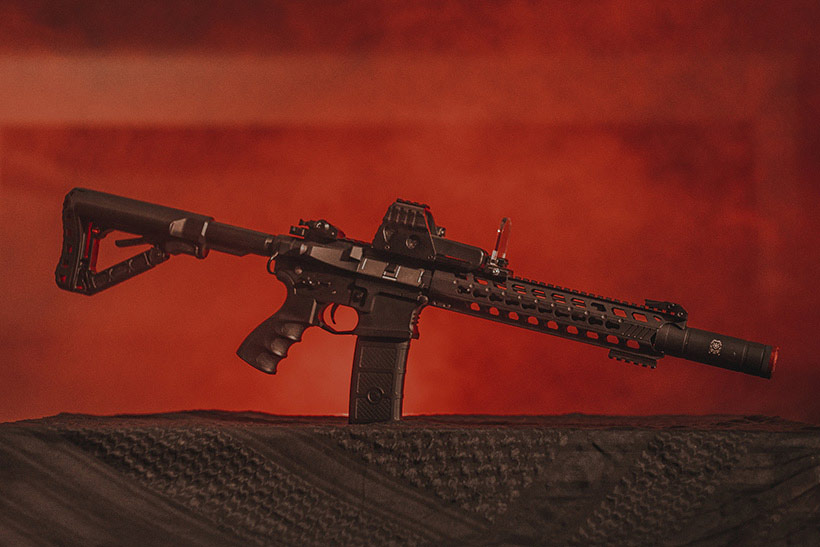 Black assault rifle with a sight protector on black textile