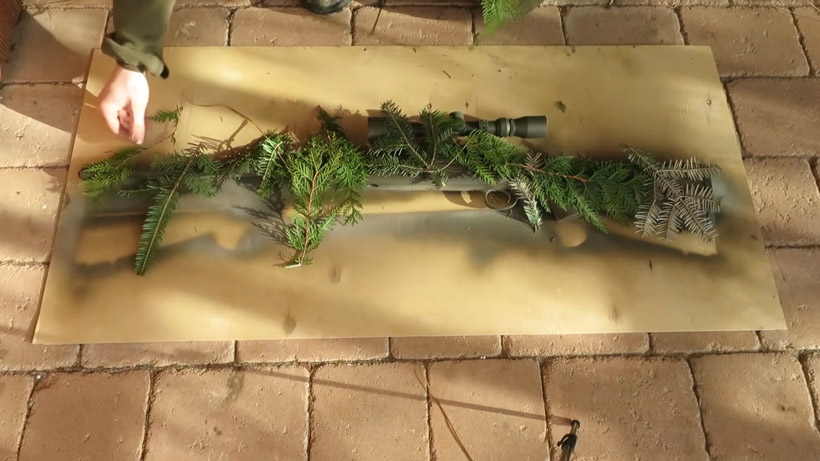 gun covered in foliage to create camo pattern